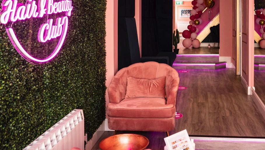 Stylish interior of Megan Eve Hair, Hinckley, England with pink chair and neon sign.