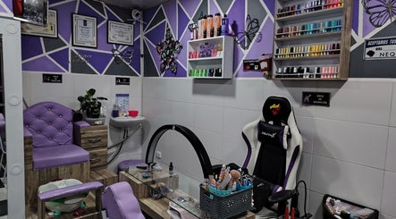 Zona de manicura moderna en NATINAILS, Bogotá, Bogotá, CO con sillas lilas y estantes de esmaltes coloridos.
