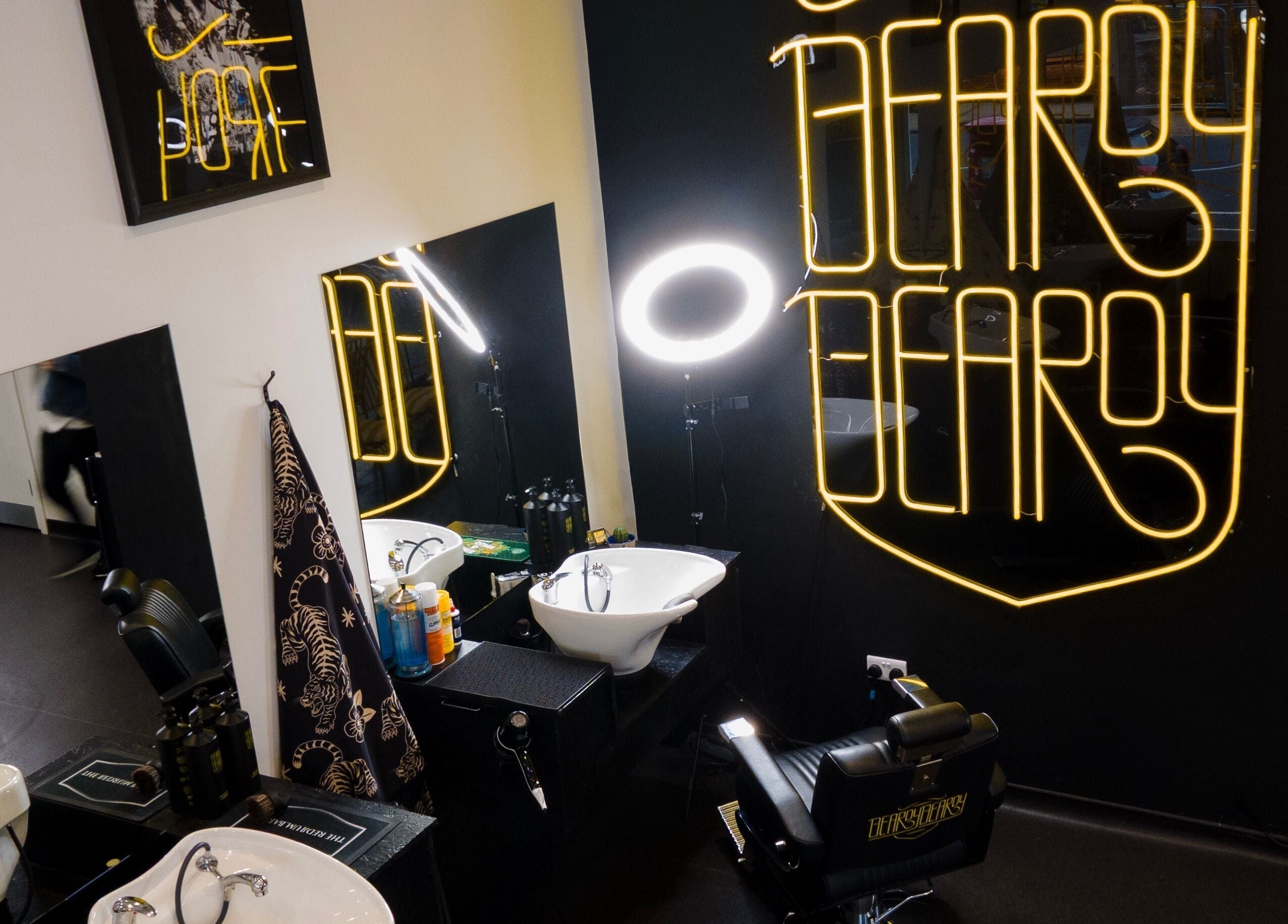 Chic interior of BeardyBeardyFinnieston barbershop in Glasgow, Scotland, featuring neon signage and modern styling chairs.