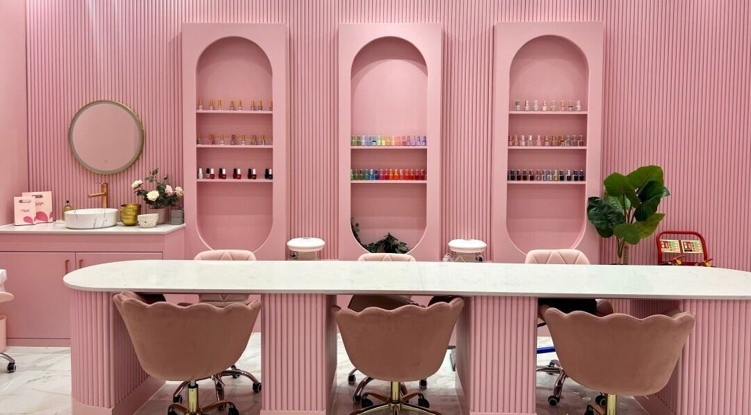 Elegant pink interior of Glam Touch Nails Salon (Female only) in London, England, GB, featuring chic chairs and nail polish display.