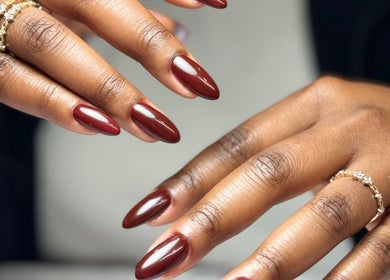 Chic Nail Studio in Arlington, Virginia, US showcases elegant garnet nail art with golden rings.