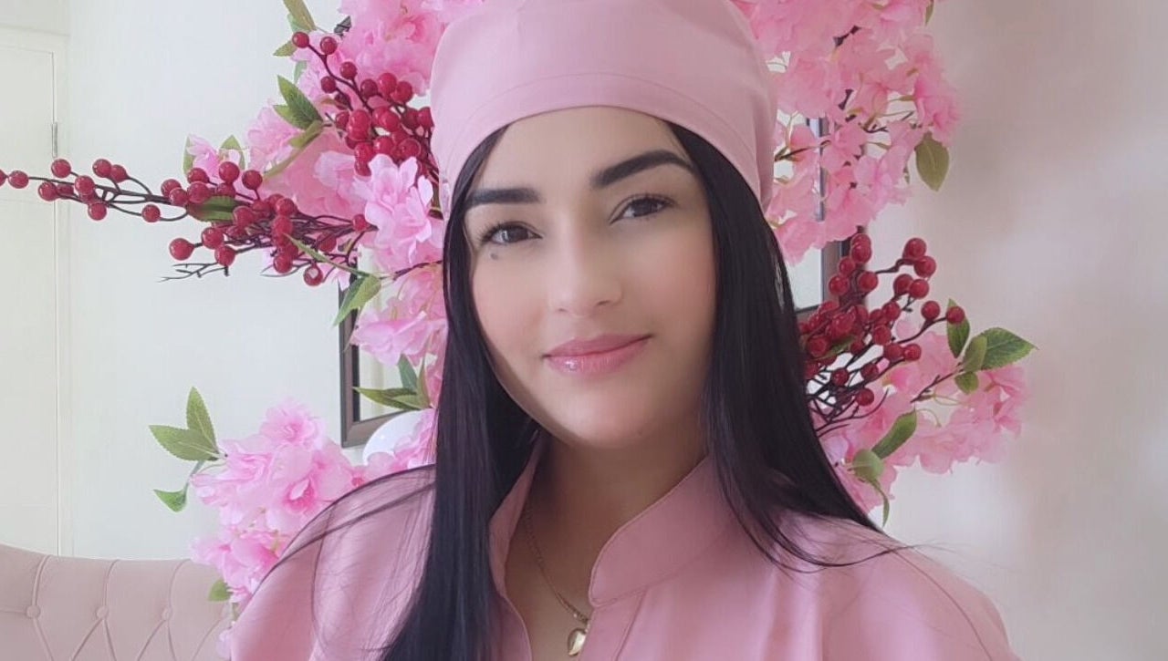 Profesional sonriente en Nails & Lashes Studio By Roxana Suares, Willemstad, Curaçao, CW con flores rosas.