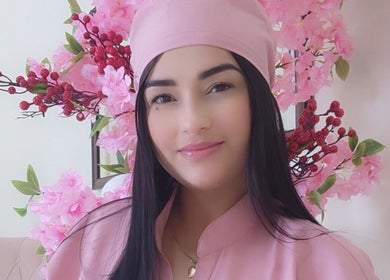 Profesional sonriente en Nails & Lashes Studio By Roxana Suares, Willemstad, Curaçao, CW con flores rosas.