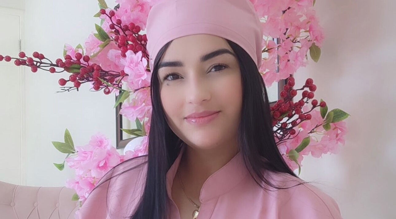 Profesional sonriente en Nails & Lashes Studio By Roxana Suares, Willemstad, Curaçao, CW con flores rosas.