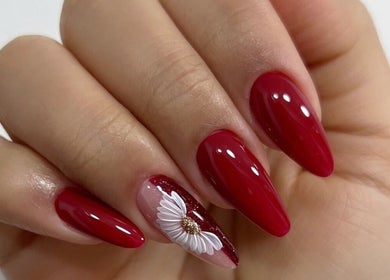Elegante diseño de uñas rojas con flor en Nails & Lashes Studio By Roxana Suares, Willemstad, Curaçao, CW.