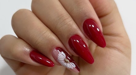 Elegante diseño de uñas rojas con flor en Nails & Lashes Studio By Roxana Suares, Willemstad, Curaçao, CW.