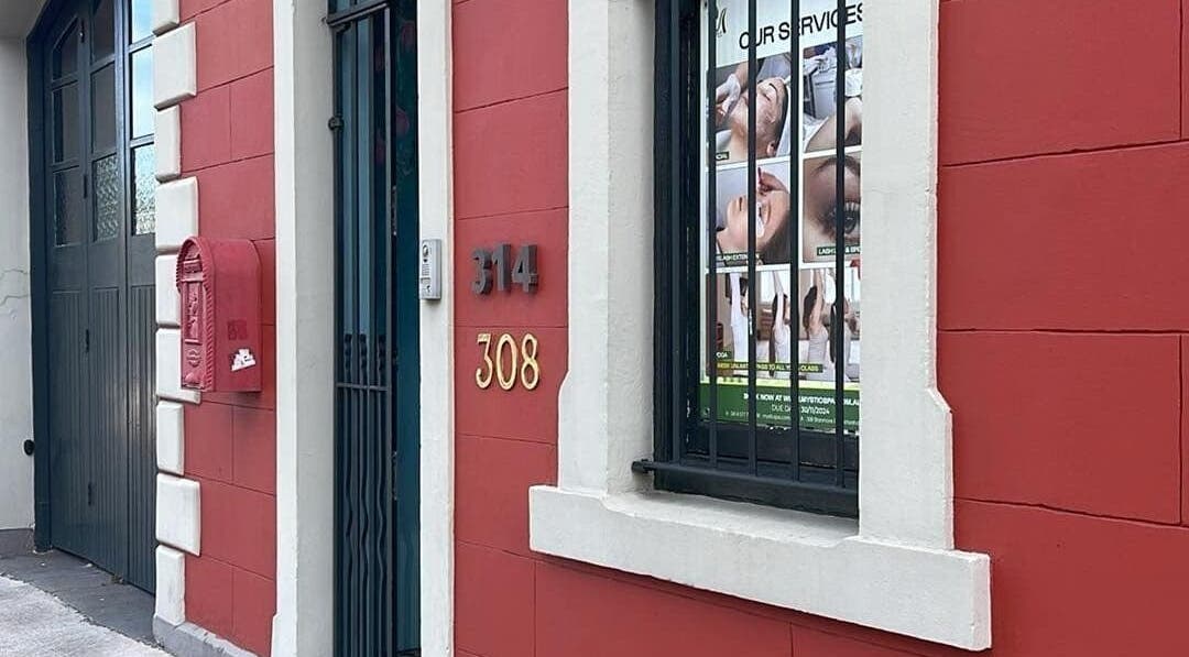 Charming facade of Mystic Spa & Wellness in Petersham, New South Wales, AU with a red wall and window display.