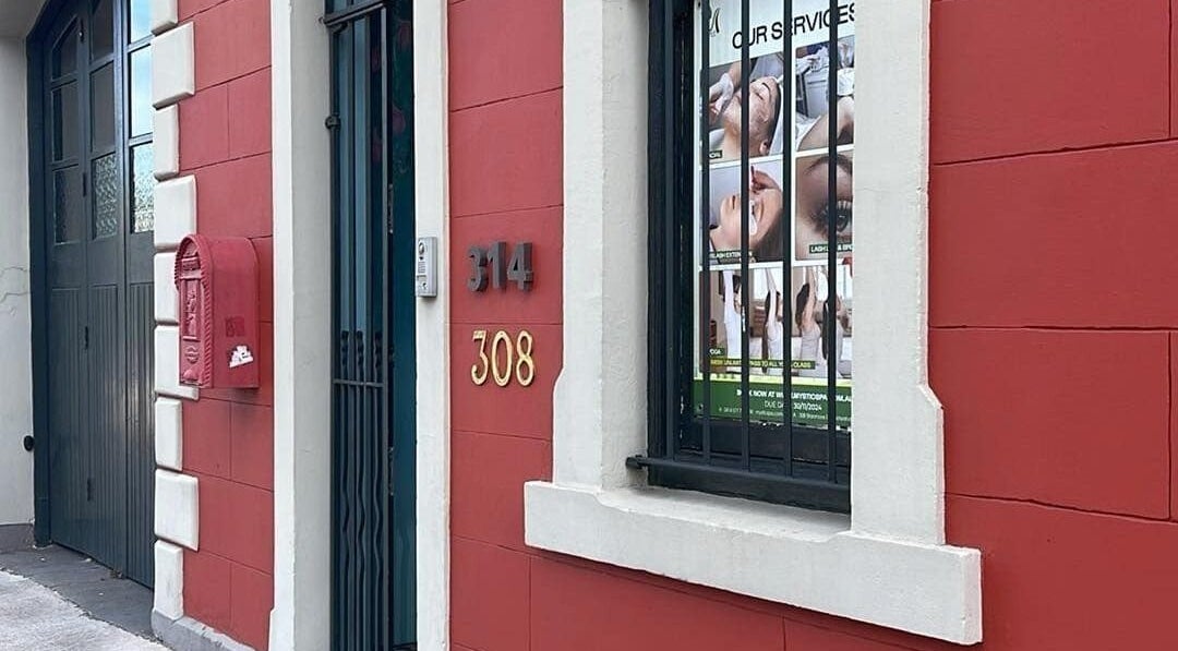 Charming facade of Mystic Spa & Wellness in Petersham, New South Wales, AU with a red wall and window display.