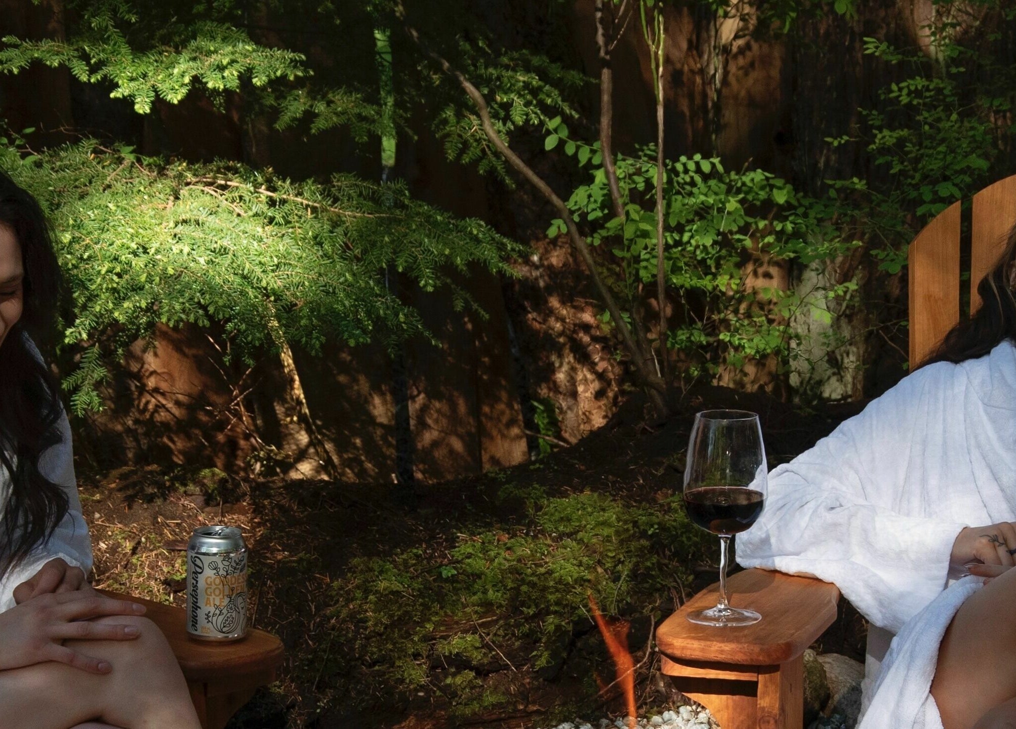 Two women laughing at The Moonshine Spa, Madeira Park, BC, surrounded by lush greenery and outdoor seating.