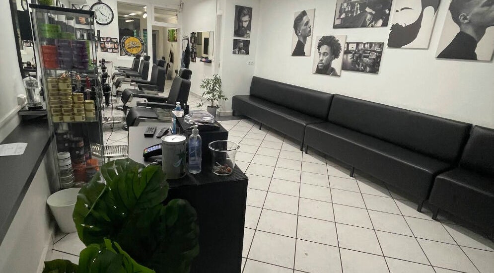 Intérieur moderne de Sculpt Barber Shop, Clermont-Ferrand, avec fauteuils et affiches murales élégantes.