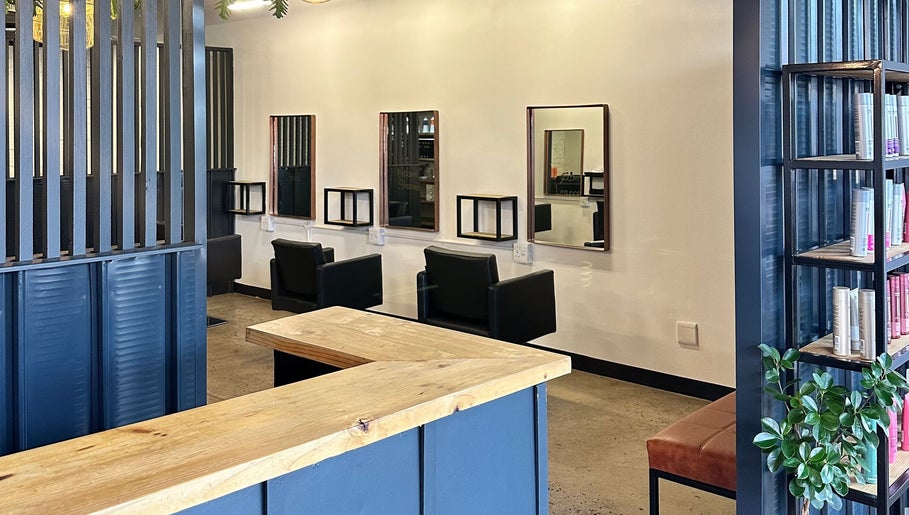 Modern salon interior at The Hair Company, Umhlanga, Kwazulu-natal, ZA featuring chairs, mirrors, and shelving.