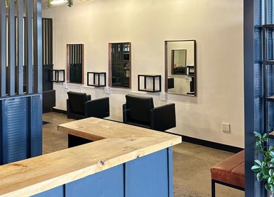 Modern salon interior at The Hair Company, Umhlanga, Kwazulu-natal, ZA featuring chairs, mirrors, and shelving.