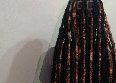 Intricate loc hairstyle at SlayedbyKy, Brighton, St. George, VC, showcasing detailed braiding.