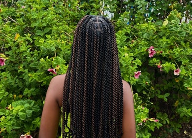 Beautiful braided hairstyle at SlayedbyKy, Brighton, St. George, VC, with vibrant floral backdrop.