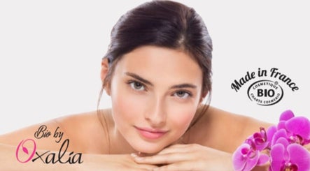 Femme souriante entourée d'orchidées à TY BEAUTÉ, VANNES, FR. Produits bio Made in France.