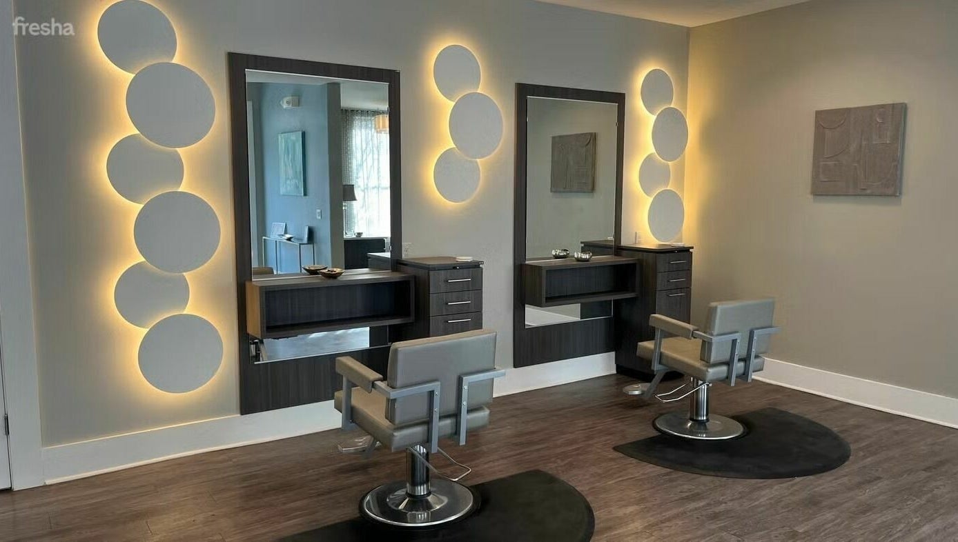 Chic salon setup at Boudoir Hair Concepts in Plano, Texas, US featuring modern styling chairs and glowing backlit mirrors.