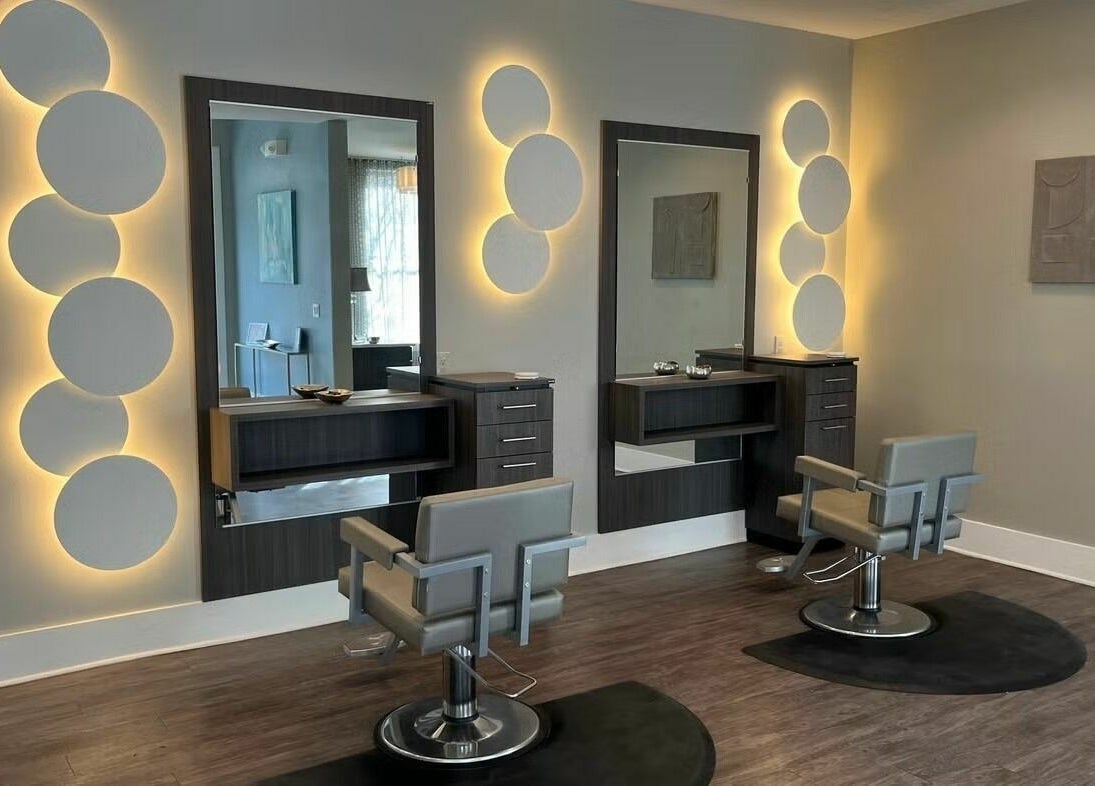 Chic salon setup at Boudoir Hair Concepts in Plano, Texas, US featuring modern styling chairs and glowing backlit mirrors.