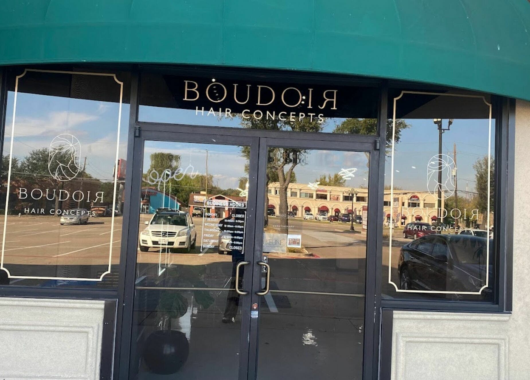 Entrance of Boudoir Hair Concepts salon in Plano, Texas, US with a green awning and glass doors.