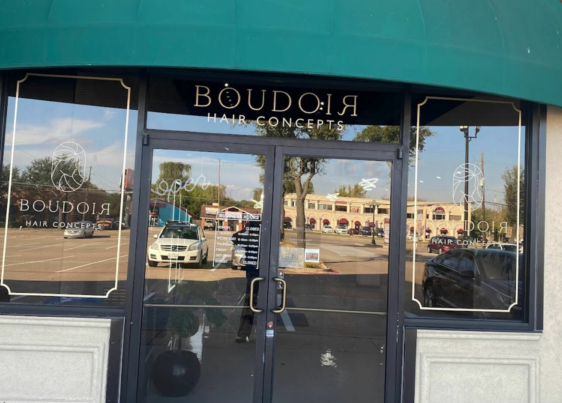 Entrance of Boudoir Hair Concepts salon in Plano, Texas, US with a green awning and glass doors.