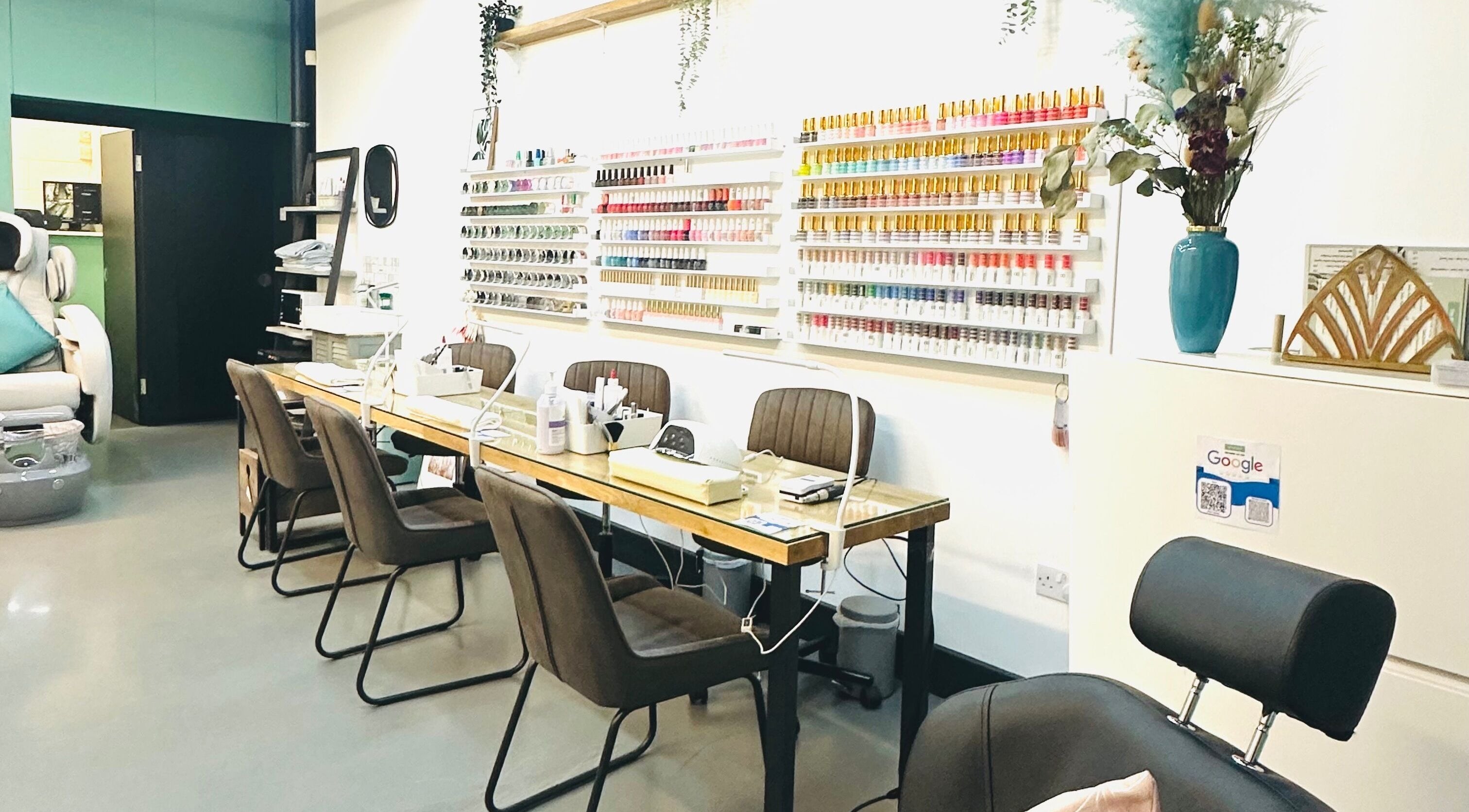 Modern nail station at The Nail Garden Soho, London, England, GB showcasing stylish seating and colorful polish display.