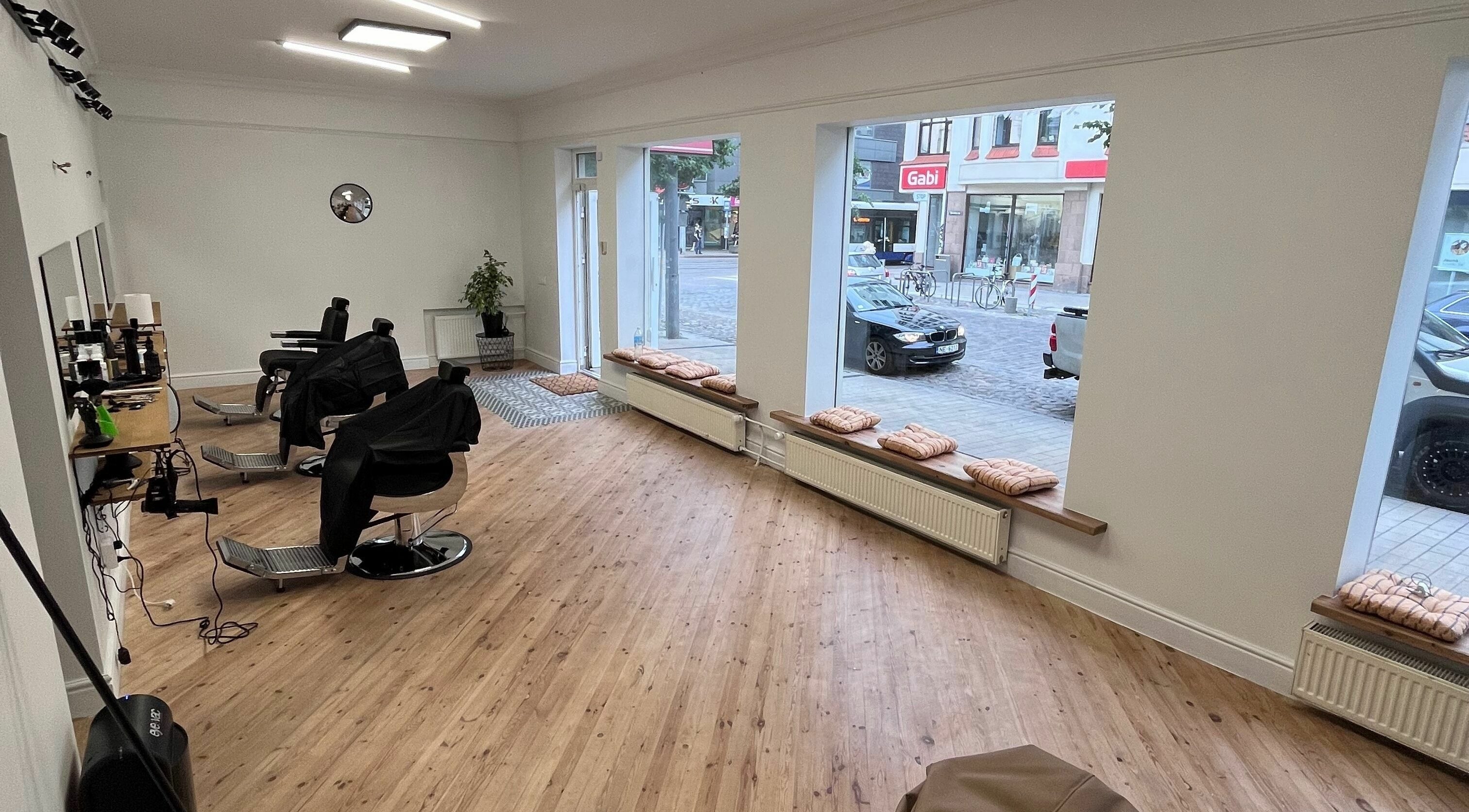 Modern interior of CutBox Barbershop in Rīga, LV, featuring sleek chairs and large windows.