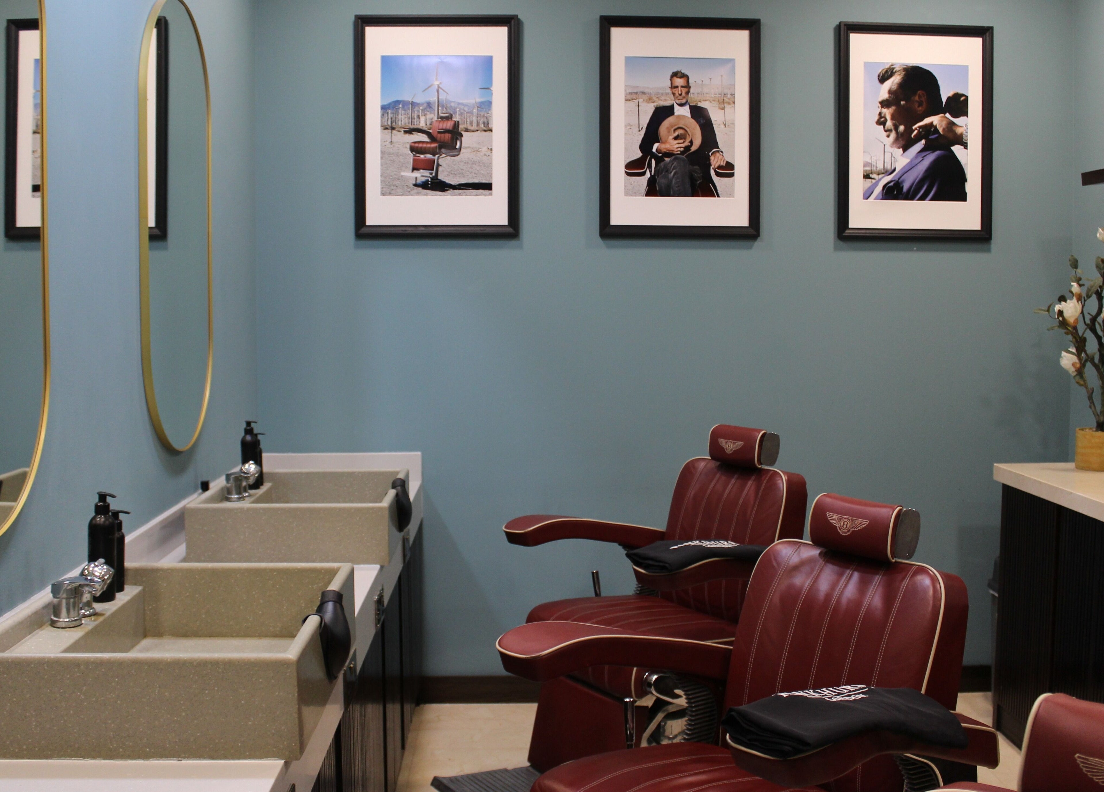 Luxurious barbershop interior at Pankhurst London, Dubai, Dubai, AE with red chairs and framed art on blue walls.