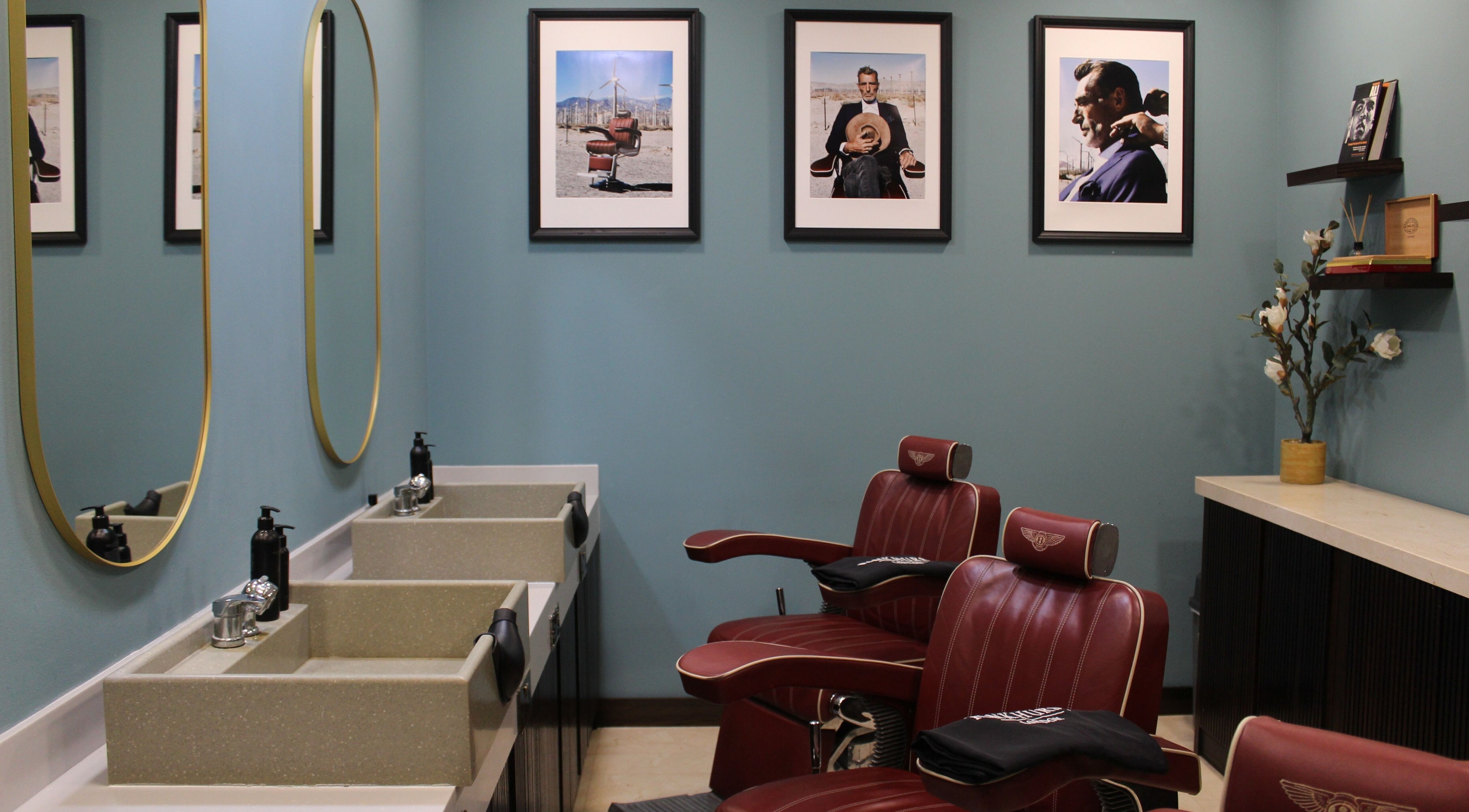 Luxurious barbershop interior at Pankhurst London, Dubai, Dubai, AE with red chairs and framed art on blue walls.