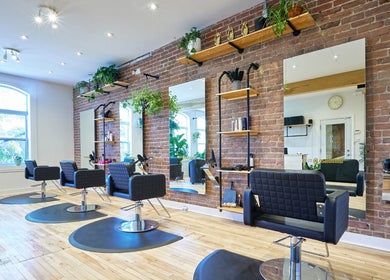 Salon élégant chez Osalon, Montréal, Québec, CA, avec chaises modernes et briques apparentes.