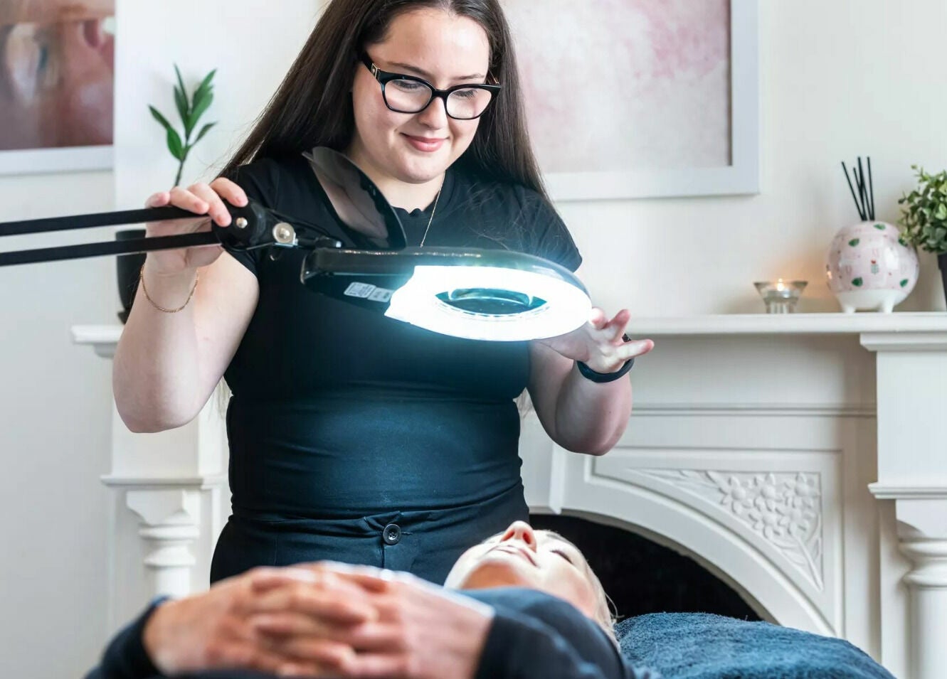 Aesthetician at Universal Advanced Skin and Body Clinic in Melbourne, Victoria, AU using a light for facial treatment.