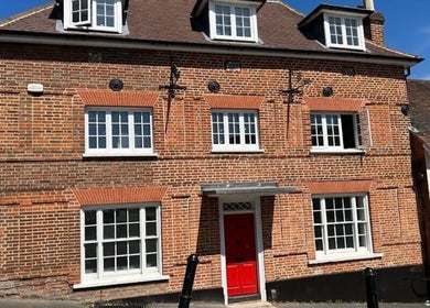 Rustic brick exterior of BONITA Spa, Guildford, England, GB, featuring a vibrant red door.