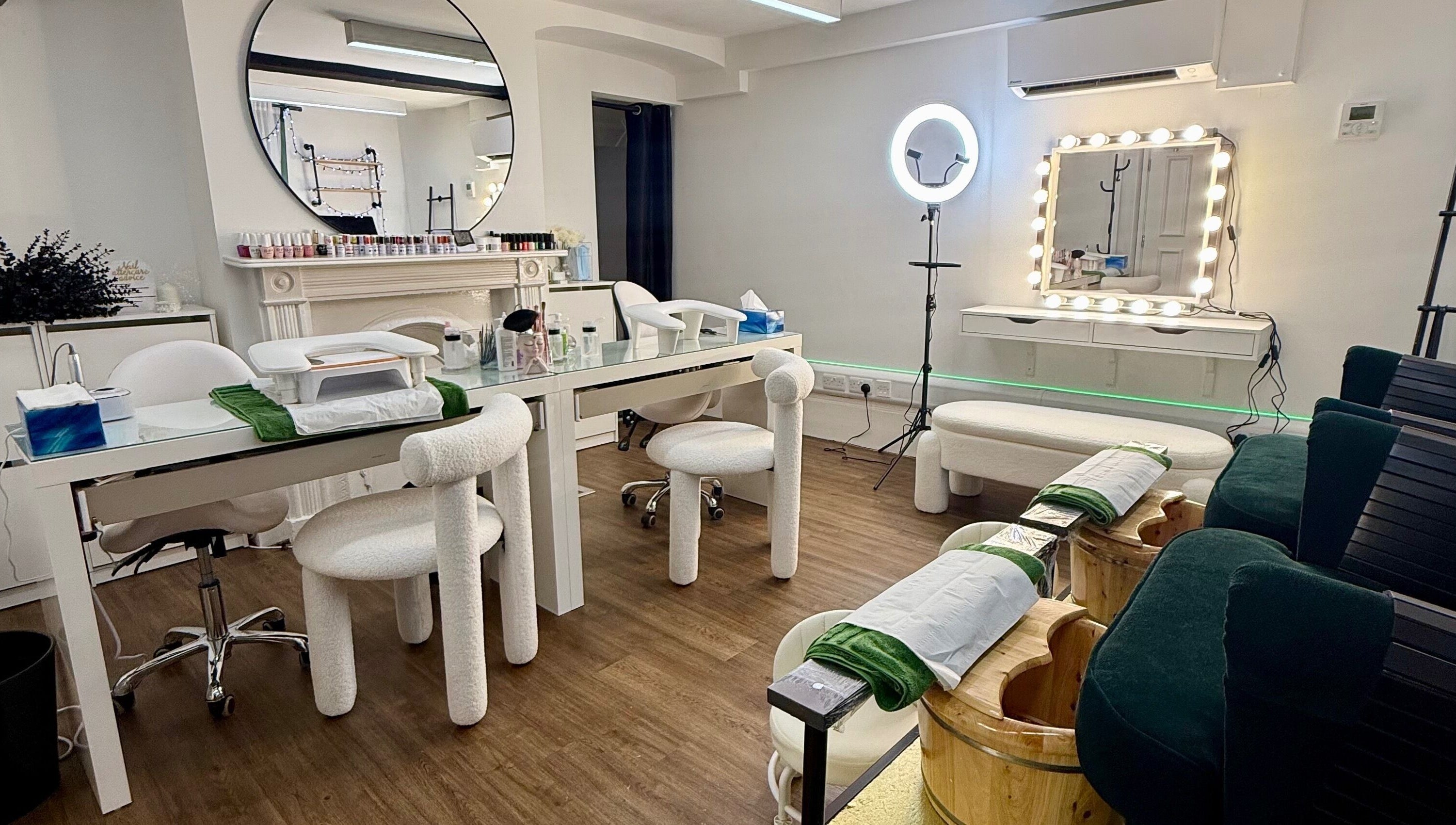 Elegant nail salon setup at Spa by BONITA, Guildford, England, GB featuring plush chairs and mirrored decor.