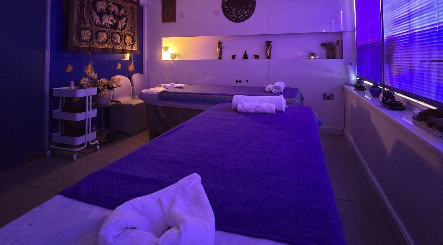 Relaxing treatment room at Panlaan Spa in Weymouth, England, GB, with soothing purple ambiance and massage beds.
