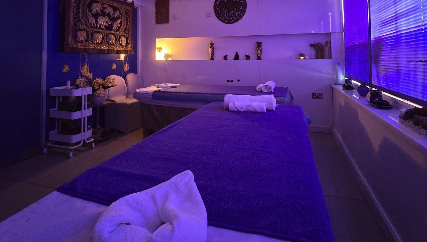 Relaxing massage room at Panlaan Spa, Weymouth, England, GB with calming blue lighting and cozy decor.