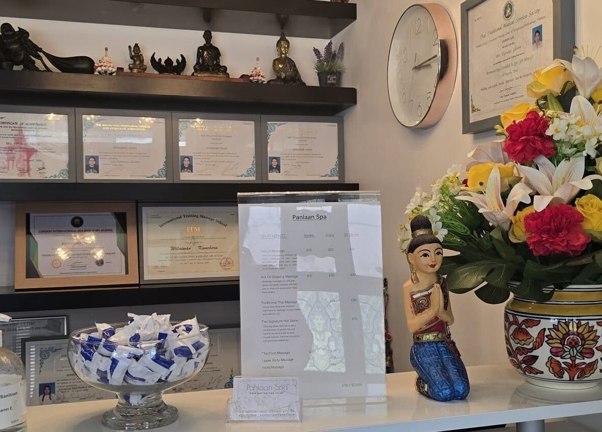 Reception display at Panlaan Spa in Weymouth, England, GB with certificates, a clock, and vibrant floral decor.