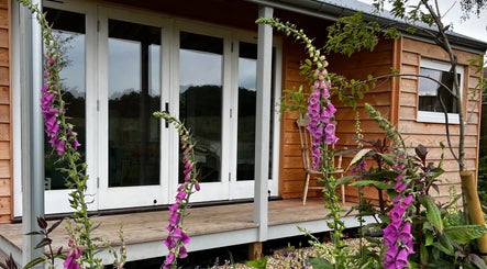 Charming lodge at Wild Coast Wellbeing in Kings Lynn, England, GB, surrounded by vibrant flowers.