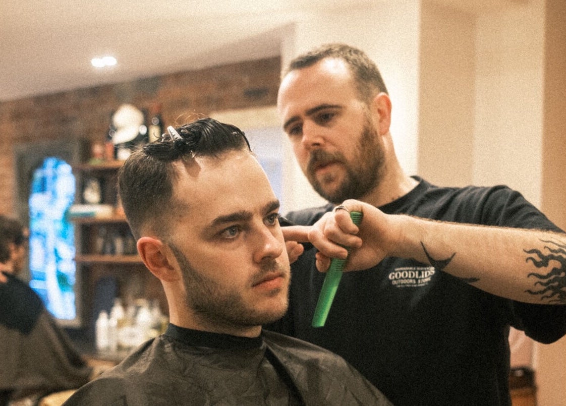 Barber expertly styling hair at time. in London, England, GB. Relaxed grooming atmosphere.