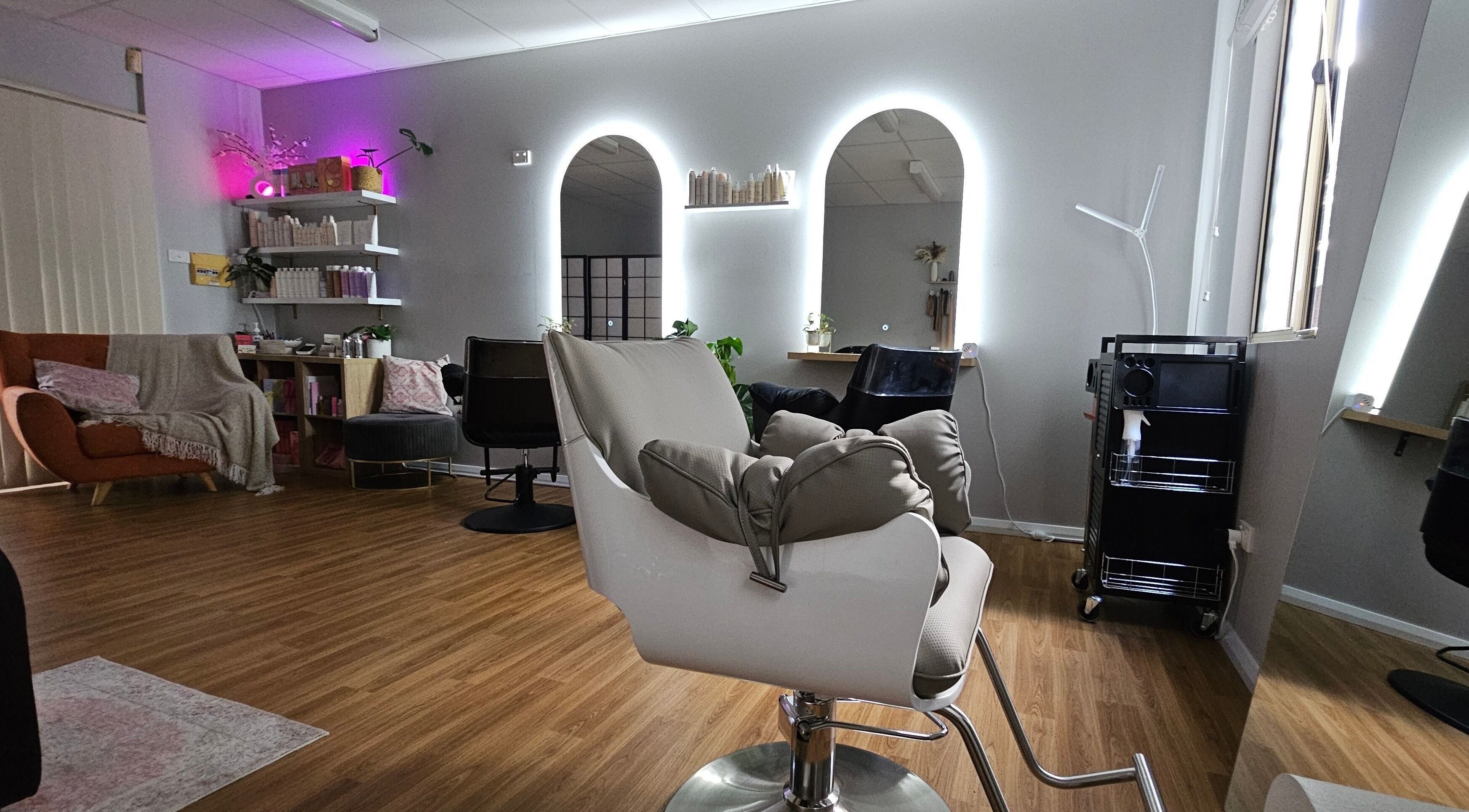 Modern salon interior at Hair By Hayley, Milpara, Western Australia, AU with stylish chairs and illuminated mirrors.