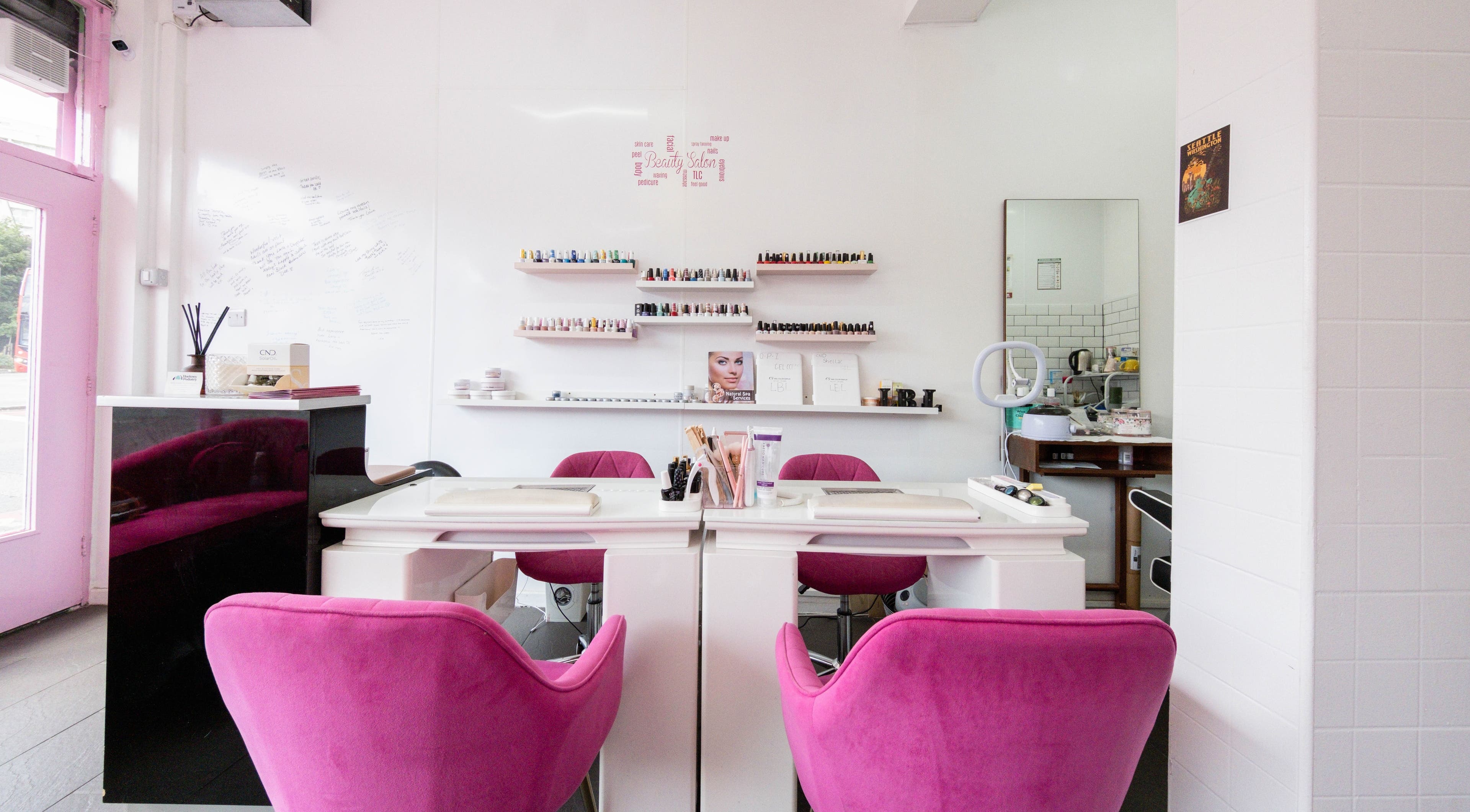 Luxurious manicure area at Lara Beauty Lounge, London, England, GB, with vibrant pink chairs and nail polishes.