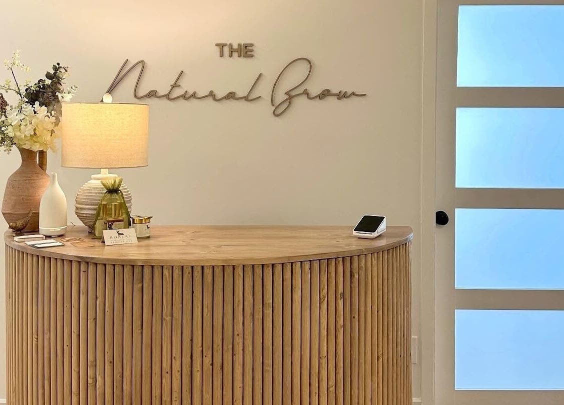 Elegant reception at The Natural Brow in Edmonton, Alberta, CA featuring a modern wooden desk and decor.