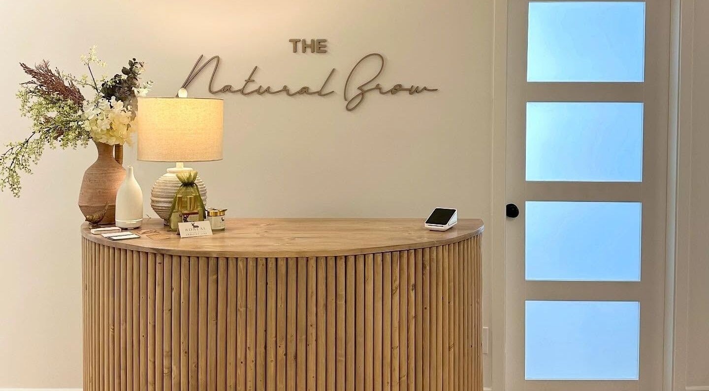 Elegant reception at The Natural Brow in Edmonton, Alberta, CA featuring a modern wooden desk and decor.