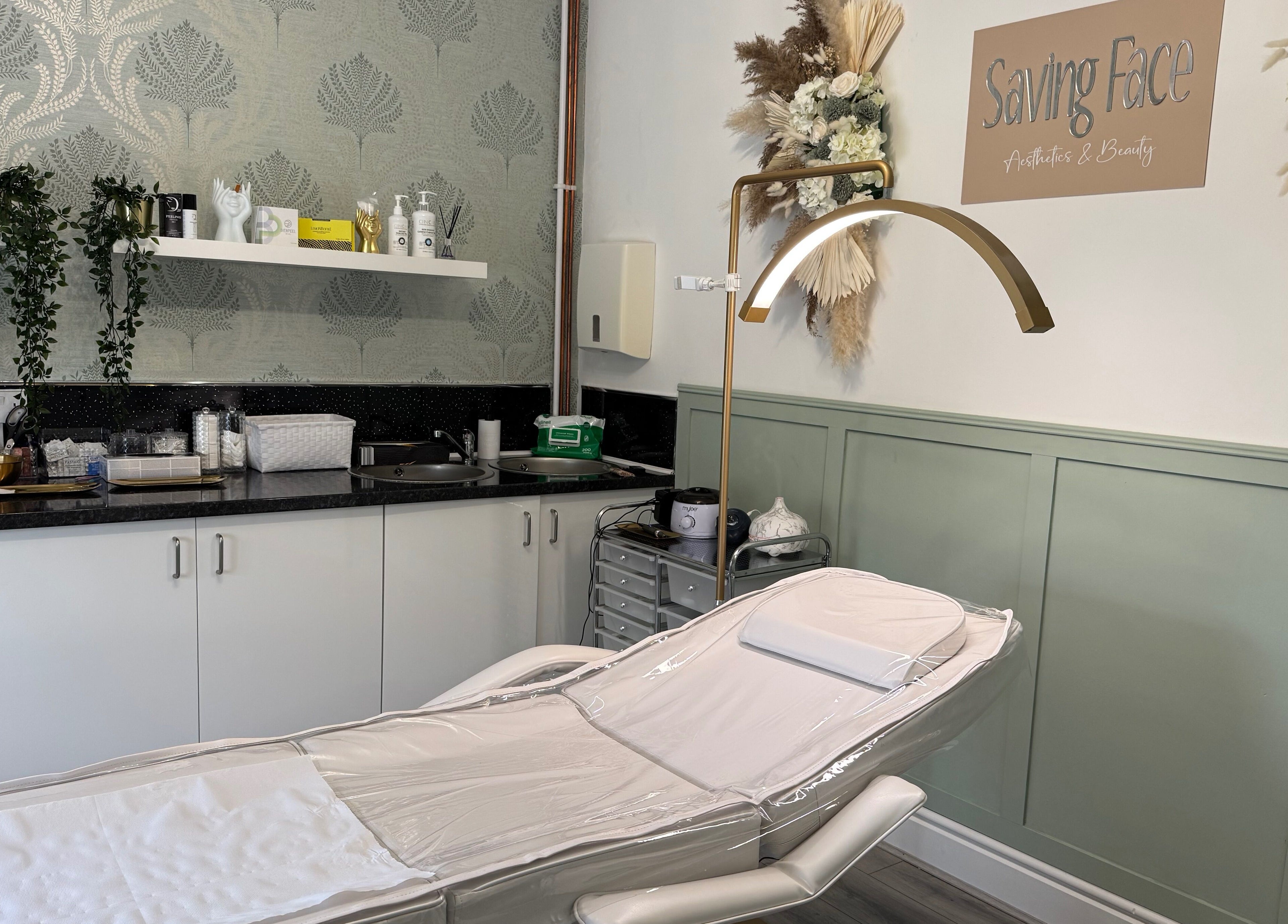 Relaxing treatment room at Saving Face Aesthetics & Beauty, Warrington, England, GB, with massage table and decor.