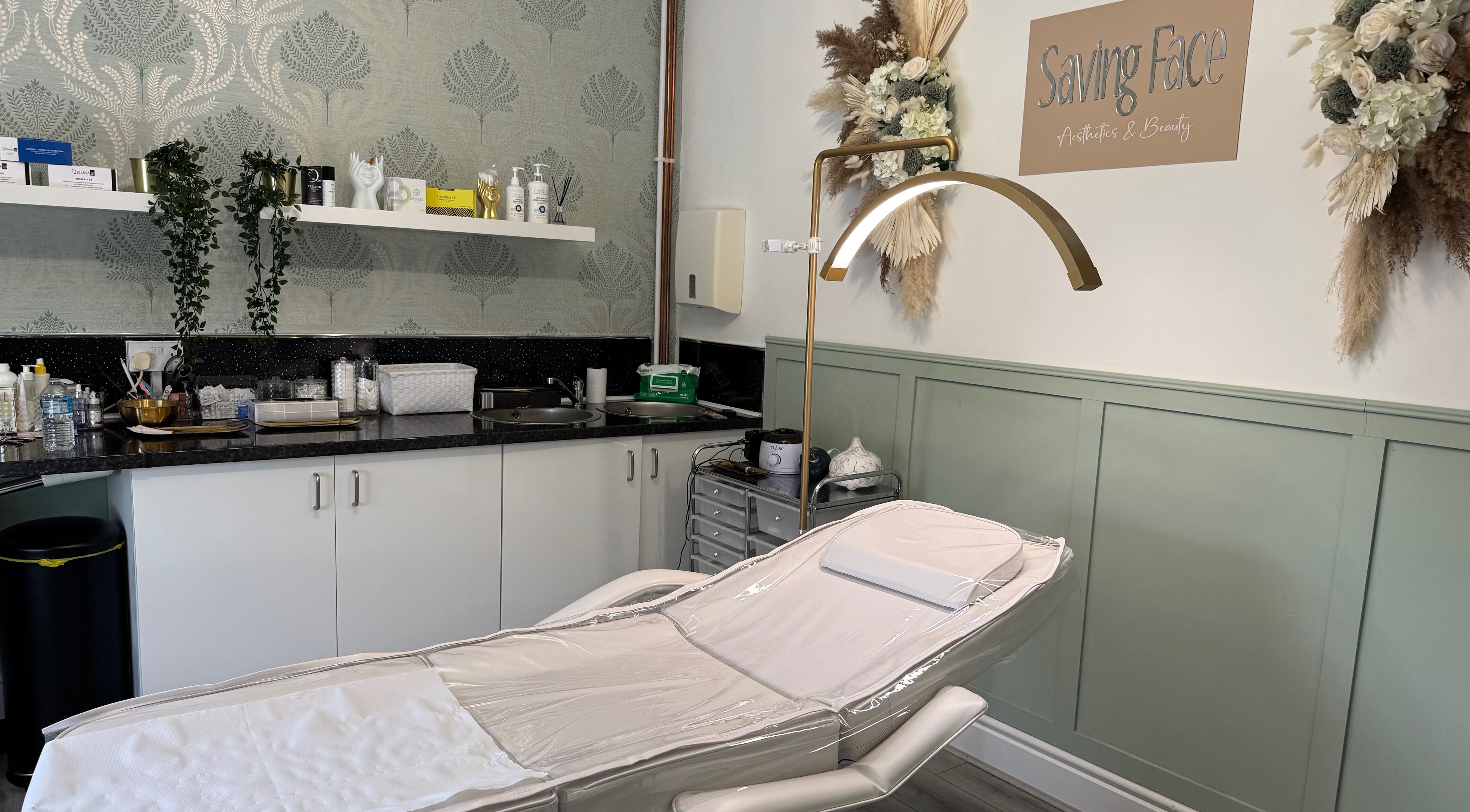 Relaxing treatment room at Saving Face Aesthetics & Beauty, Warrington, England, GB, with massage table and decor.