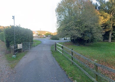 Entrance gate to Enchanted By Em, a serene beauty venue in Narborough, England, GB, surrounded by lush greenery.