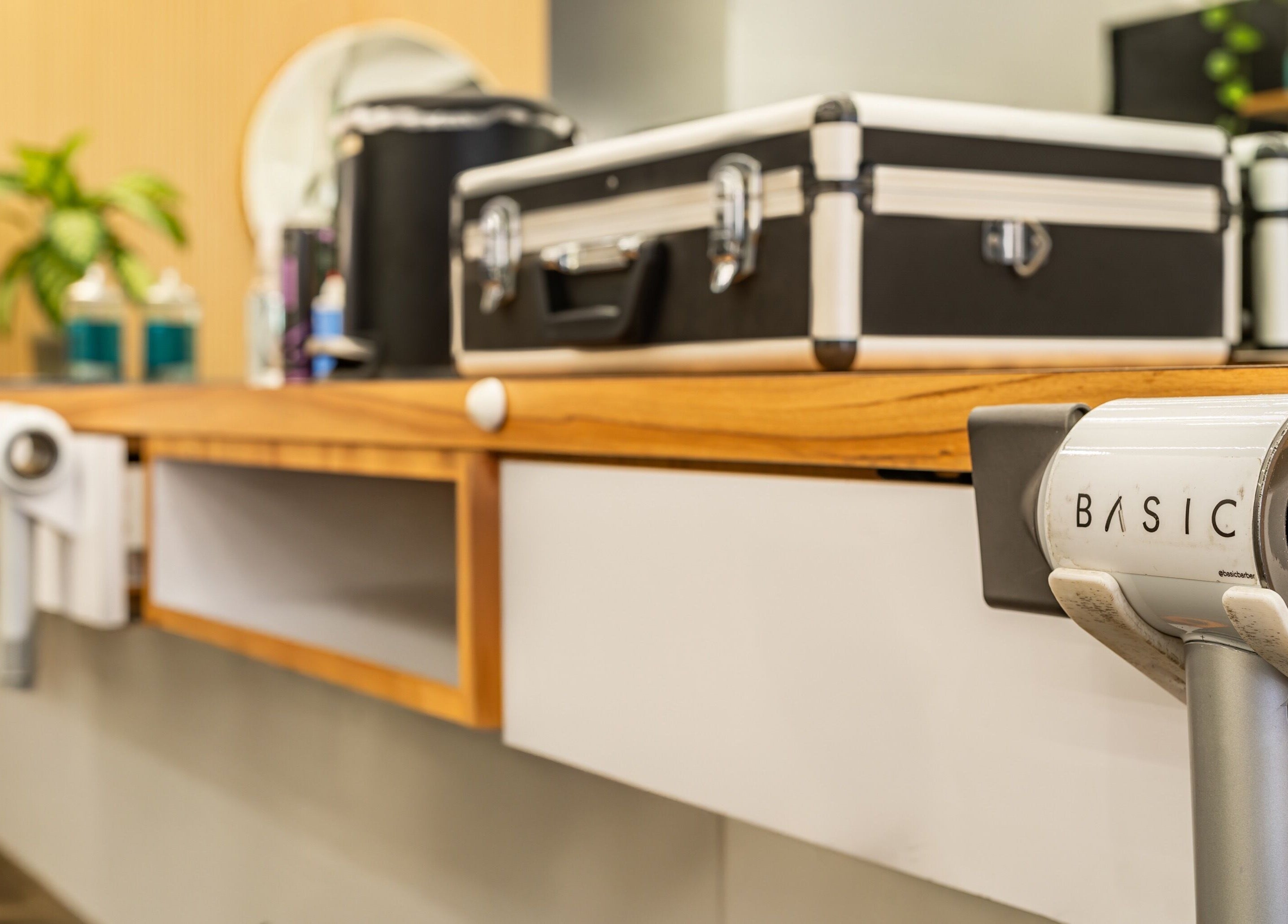 Detailed barber station at Basic Barber, Costa Mesa, California, US with plants and styling tools.