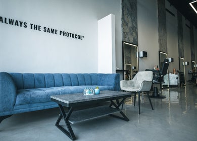 Modern interior of The Protocol Barbershop in Riyadh with blue couch and sleek barber stations.