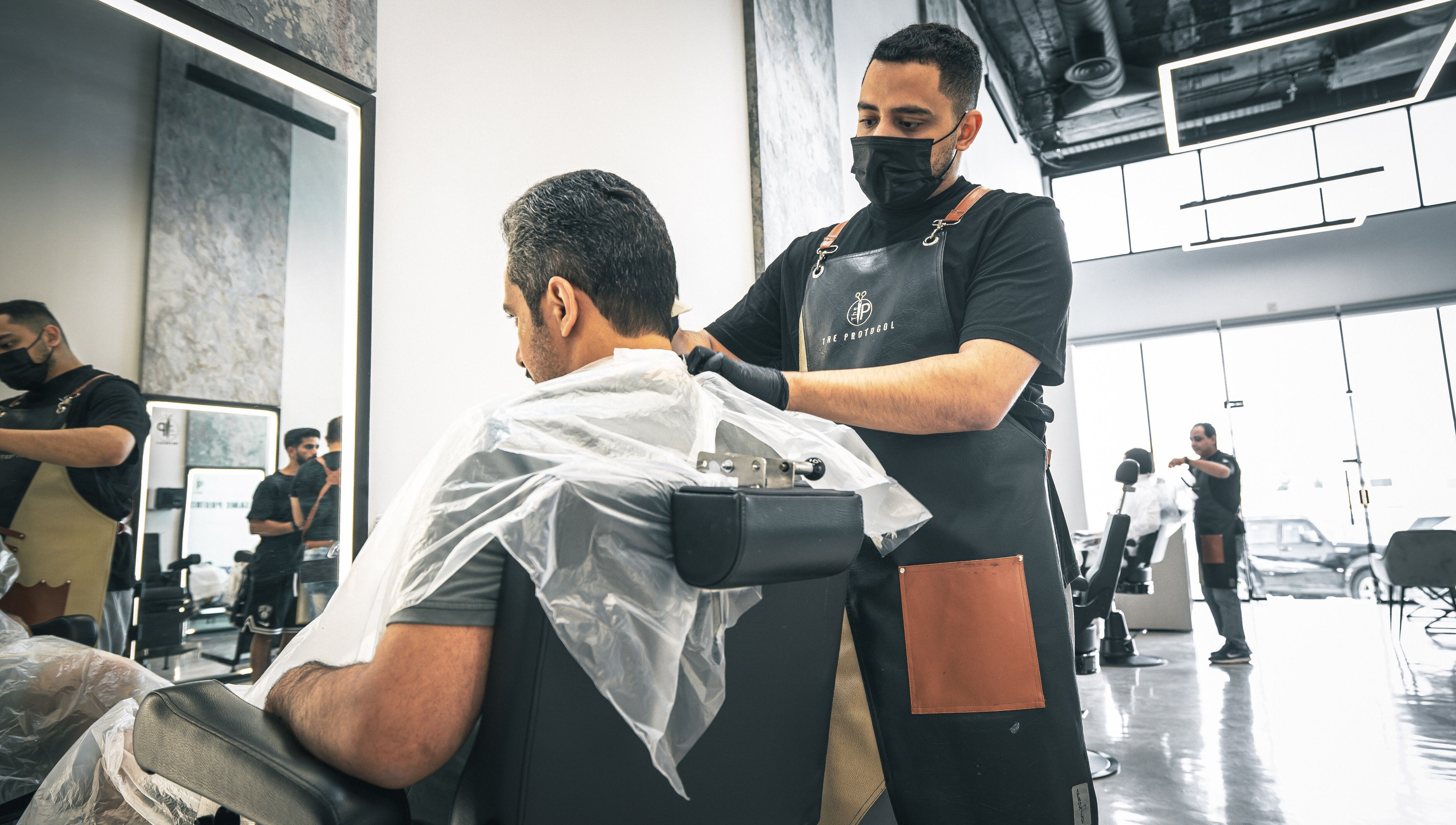A skilled barber at The Protocol Barbershop in Riyadh, Riyadh Province, SA, expertly trims a client's hair.