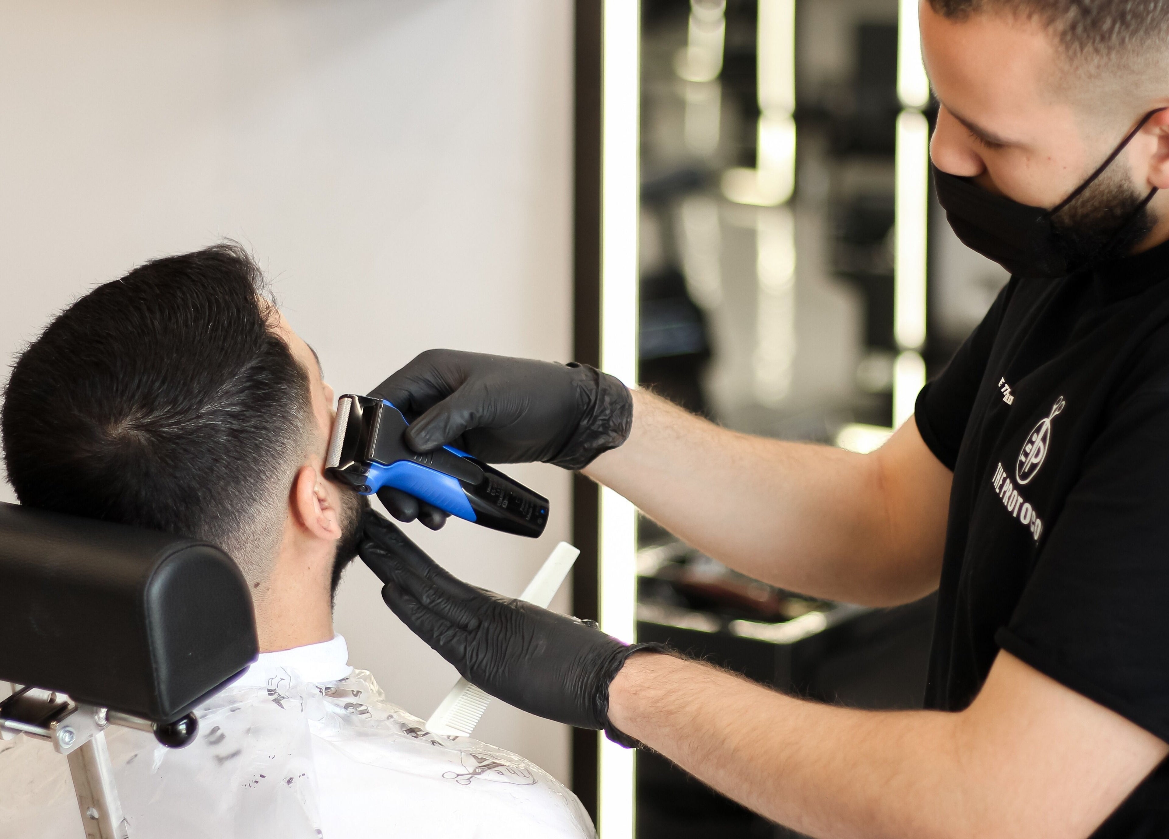 Expert barber at The Protocol Barbershop, Riyadh precisely trimming client's hair.