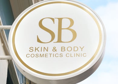 Exterior sign of SB Cosmetics Clinic, Glasgow, Scotland, GB, featuring gold lettering on a round design.