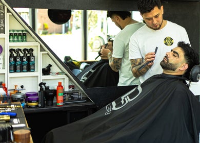 Barber expertly grooming client at DG Barbershop in Guildford, England, GB.