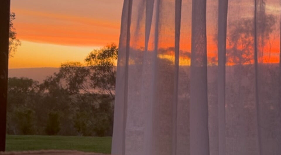 Beautiful sunset view through sheer curtains at Face Lane, Castlereagh, New South Wales, AU.